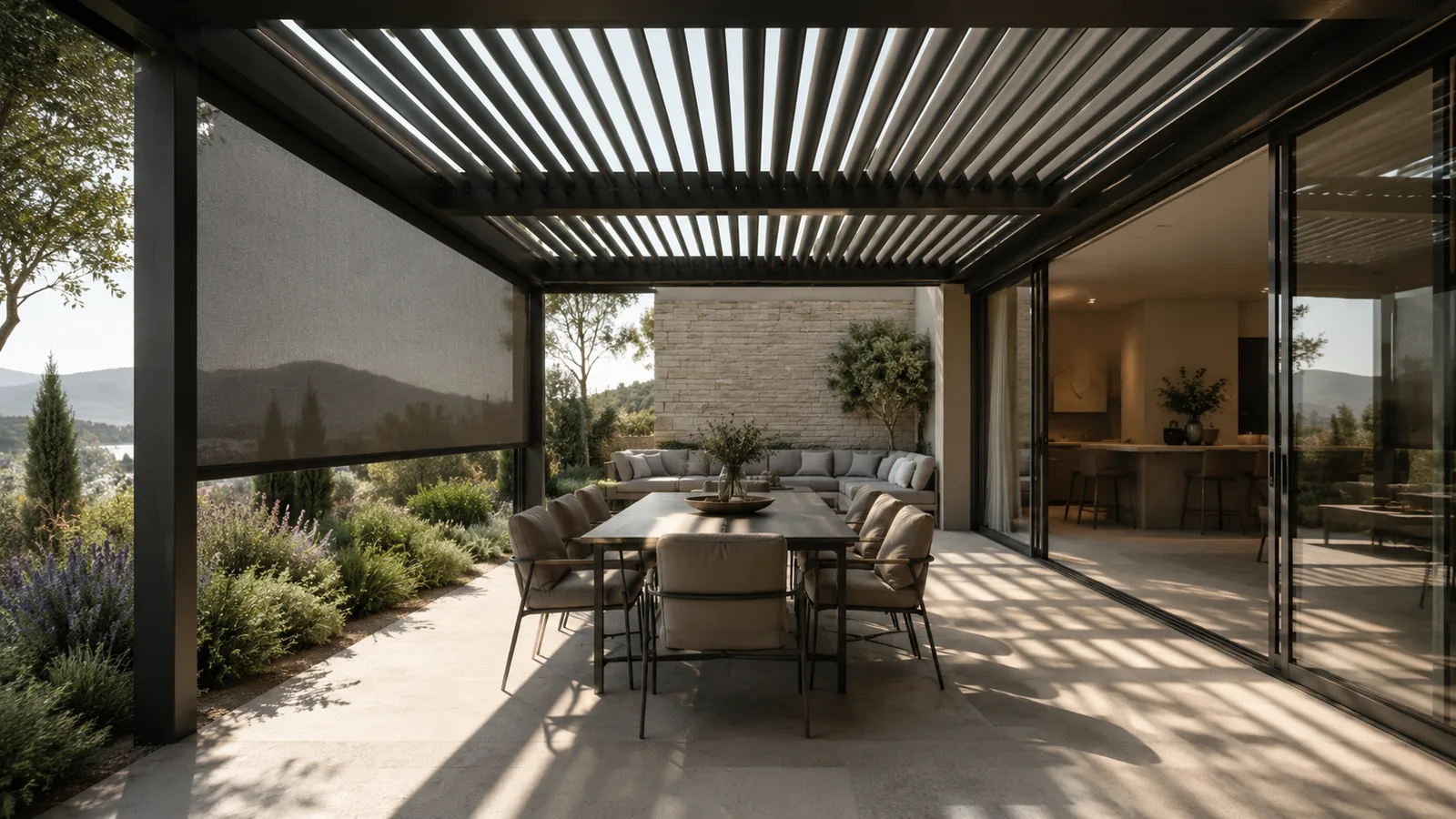 Pergola bioclimatica in alluminio scuro con lamelle orientabili e screen laterale, sopra una zona pranzo esterna che si apre sul soggiorno