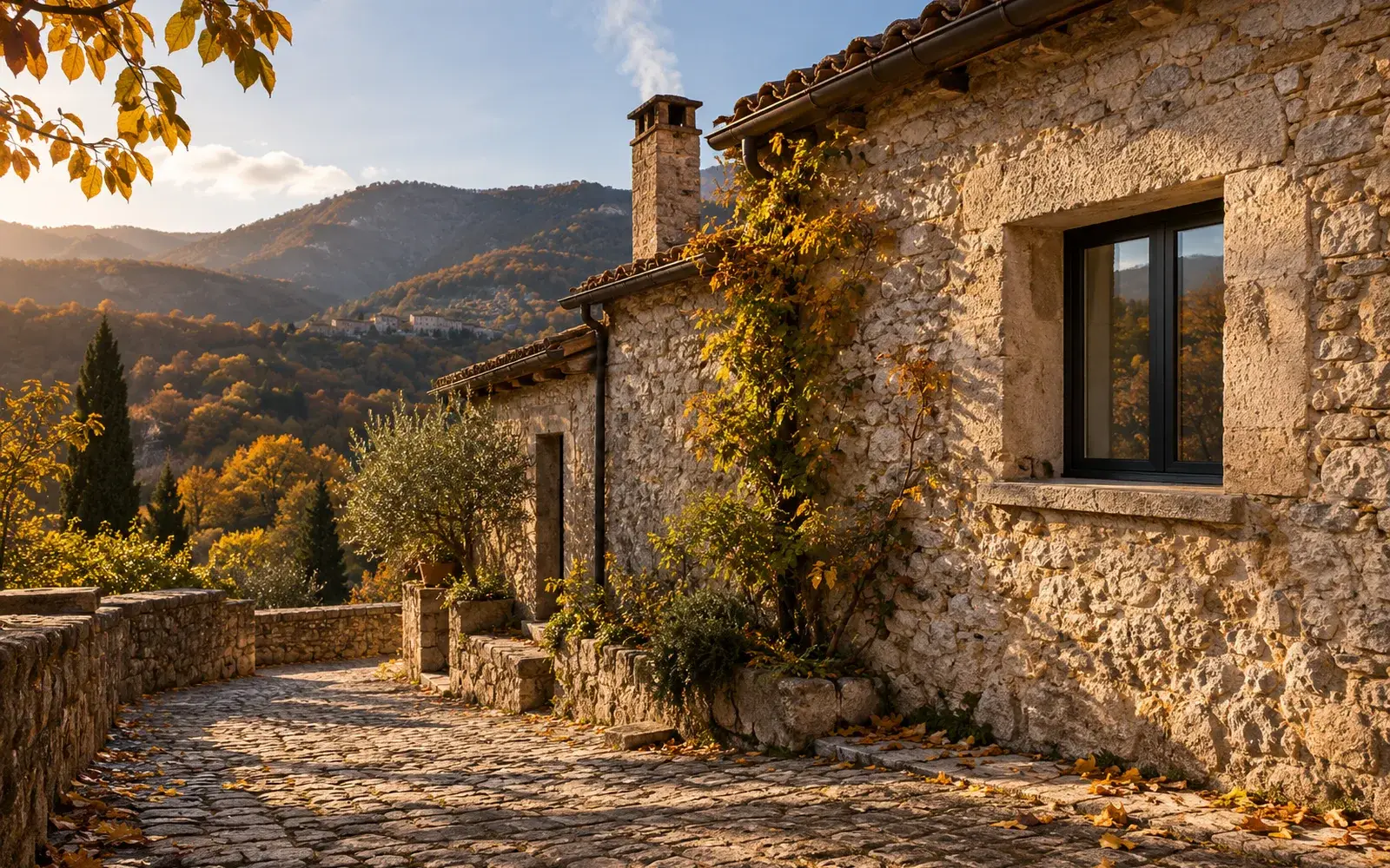 Casa di paese in pietra della valle dell’Aniene in una luce di fine ottobre, con una finestra dal telaio nero infilata in fondo a un muro profondo