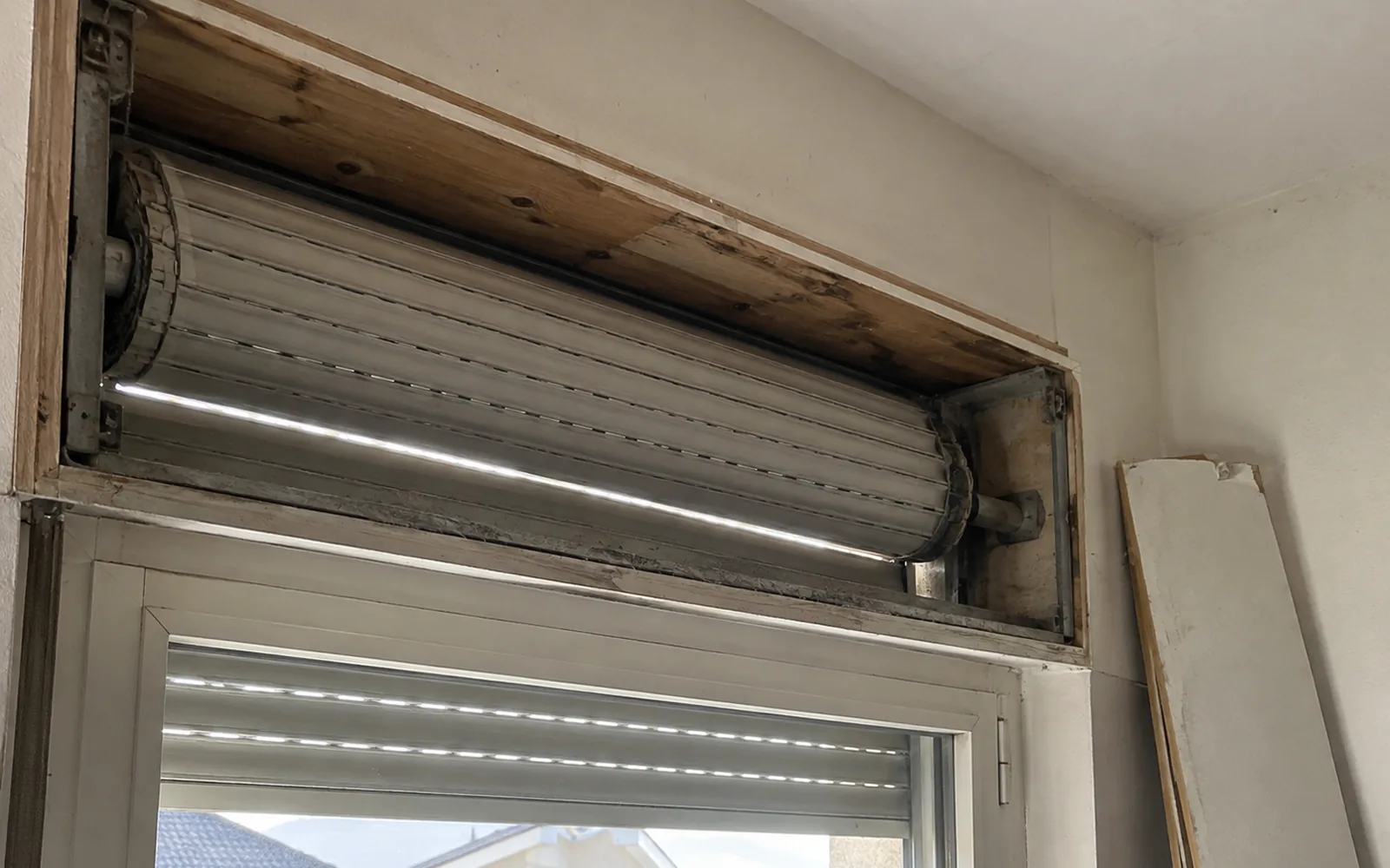Cassonetto della tapparella aperto per l’ispezione, con il rullo avvolto e l’interno in legno senza isolamento