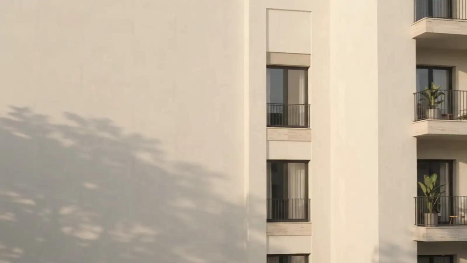 Facciata chiara di un condominio con finestre e balconi, nella luce del pomeriggio