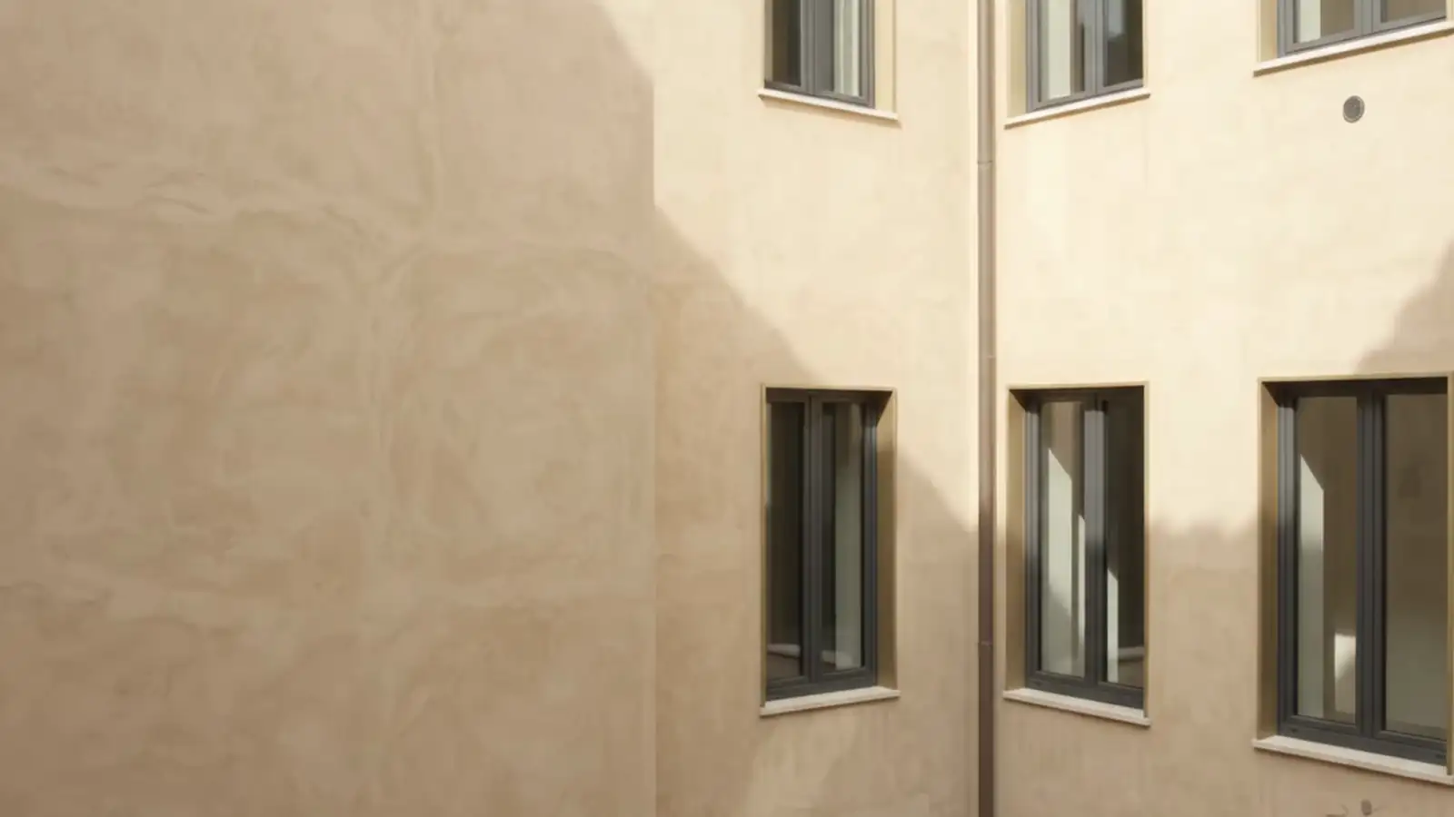 Cortile interno con facciate color sabbia e finestre dal telaio scuro